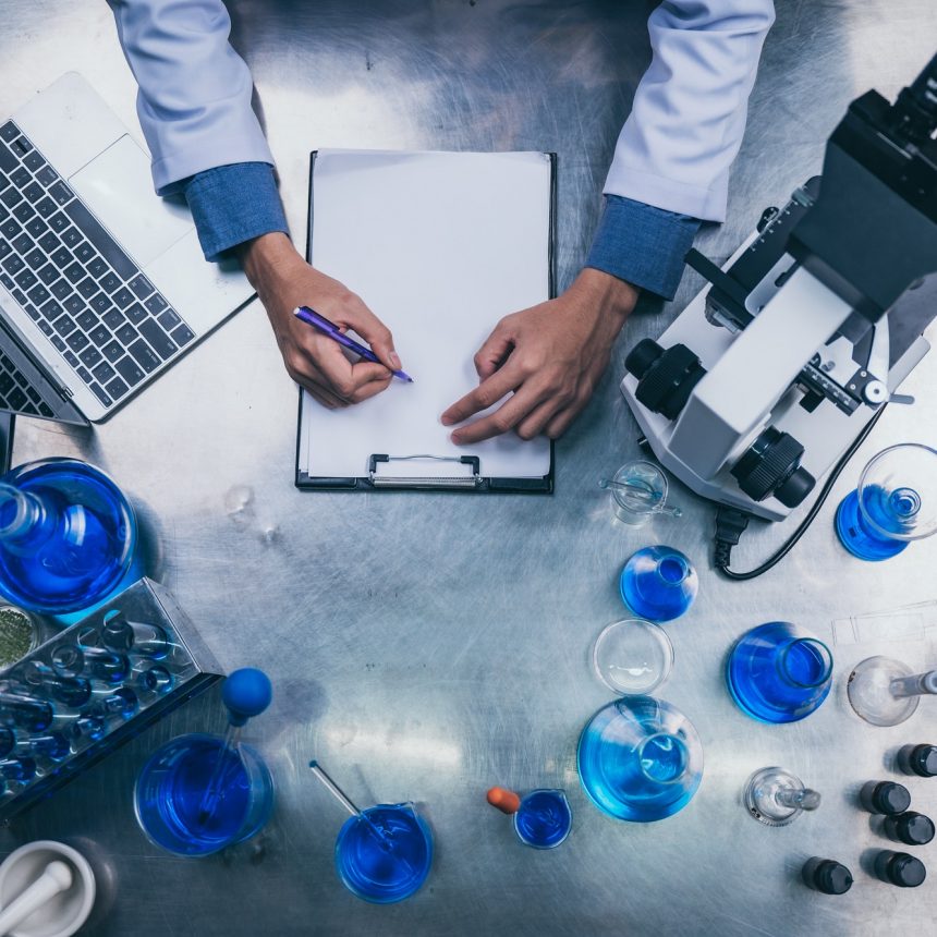 top view workspace in laboratory with microscope, laptop, and laboratory tools